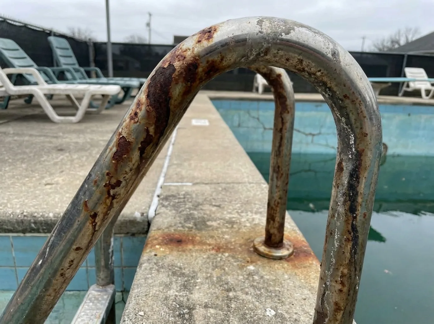Escalera metálica con corrosión visible en entorno de piscina